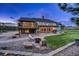 Inviting home exterior with a large glass sunroom, stone patio, fire pit, and well-manicured lawn at 18045 Sunburst Dr, Monument, CO 80132