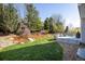 A landscaped backyard with mature trees and a grey wood deck featuring outdoor seating at 1009 Monarch Way, Superior, CO 80027