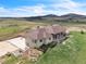 An aerial view of the beautiful home nestled in a green landscape with a mountain backdrop at 15125 Spring Valley Rd, Larkspur, CO 80118