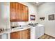 Laundry room with wooden cabinetry above washer and dryer, sink with countertops, and decor signs on the wall at 15125 Spring Valley Rd, Larkspur, CO 80118