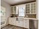 Bright kitchen featuring a farmhouse sink, white cabinets, and herringbone backsplash at 4818 Bryant St, Denver, CO 80221