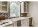 Close-up of kitchen sink featuring a window, white cabinets, and herringbone backsplash at 4818 Bryant St, Denver, CO 80221