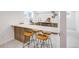 Bright kitchenette island featuring a quartz countertop with wooden cabinets and modern wooden bar stools at 4818 Bryant St, Denver, CO 80221