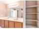 Primary bathroom with dual sinks, vanity, large mirror, and walk-in closet with built-in shelves at 27615 E Archer Ave, Aurora, CO 80018