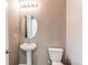 Stylish powder room with a pedestal sink, oval mirror, and modern light fixture at 27615 E Archer Ave, Aurora, CO 80018
