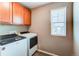 Well-equipped laundry room with washer, dryer, overhead cabinets, and natural light from window at 27615 E Archer Ave, Aurora, CO 80018