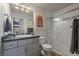 Bathroom with gray cabinets, modern fixtures, a glass-enclosed shower, and colorful modern wall art at 1143 Hummingbird Cir, Longmont, CO 80501