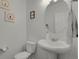 Half-bathroom featuring a toilet, pedestal sink, a round mirror, and modern fixtures and decor at 12685 E 104Th Pl, Commerce City, CO 80022