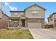 Two-story home featuring stone accents, a two-car garage, and a well-maintained front yard at 12685 E 104Th Pl, Commerce City, CO 80022