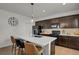 Well-lit kitchen showcasing an island with a white countertop, dark cabinets, and stainless steel appliances at 12685 E 104Th Pl, Commerce City, CO 80022