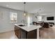 Spacious kitchen island with an undermount sink, dark cabinetry, and a view of the dining and living areas at 12685 E 104Th Pl, Commerce City, CO 80022