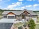 Charming home featuring a stone facade, cedar accents, a three-car garage, and professionally landscaped front yard at 17275 Gwilym Ct, Monument, CO 80132
