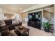 Comfortable living room features a brown leather sofa, media center, and staircase access at 17275 Gwilym Ct, Monument, CO 80132