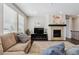 Inviting living room featuring a stone fireplace, large windows, and comfortable sofa at 7968 E 152Nd Dr, Thornton, CO 80602