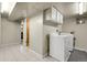 Bright laundry room featuring tile flooring, white appliances, and overhead cabinets at 4108 S Inca St, Englewood, CO 80110