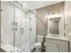 Modern bathroom featuring white marble tile, a glass enclosed shower, stone floors, and a bright vanity with stone countertop at 8783 S Winnipeg Ct, Aurora, CO 80016