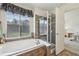 Bright bathroom featuring a soaking tub, glass-enclosed shower, and large window with privacy blinds at 2864 S Jebel Way, Aurora, CO 80013
