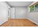 Bedroom with light gray walls, wood floors, and a view into a bathroom with tiled shower at 11625 Bellaire Way, Thornton, CO 80233