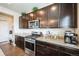 Kitchen with stainless steel appliances, granite counters, coffee maker, and dark-stained cabinets at 6954 E 117Th Ave, Thornton, CO 80233