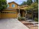 Two story home with golden yellow siding, concrete driveway, a two car garage and stone accents around the porch at 10247 Telluride Way, Commerce City, CO 80022