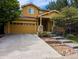 Two story home with golden yellow siding, concrete driveway, a two car garage and stone accents around the porch at 10247 Telluride Way, Commerce City, CO 80022