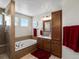 Bright bathroom featuring a glass shower, soaking tub, single vanity, and tile flooring at 13804 W 61St Cir, Arvada, CO 80004