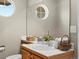Bathroom featuring round window, white tiled counter, basket with rolled towels, and wood vanity at 13804 W 61St Cir, Arvada, CO 80004
