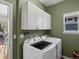 Well-lit laundry room includes updated washer and dryer and ample cabinet storage at 13804 W 61St Cir, Arvada, CO 80004