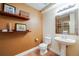 Cozy bathroom featuring a pedestal sink, tile floors, neutral walls, and framed artwork on floating shelves at 7329 Arco Iris Ln, Castle Pines, CO 80108