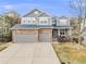 Attractive two-story home with a stone and gray facade, a three-car garage, and a well-maintained lawn at 7329 Arco Iris Ln, Castle Pines, CO 80108