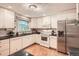 Bright kitchen featuring white cabinets, stainless steel appliances, black countertops, and wood floors at 1048 N Columbine St, Golden, CO 80403