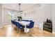 Elegant dining room with a long table, blue velvet chairs, hardwood floors, and modern lighting at 8623 S Wadsworth Ct, Littleton, CO 80128