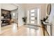 Bright foyer with hardwood floors, stylish console table, plants, and modern paneled glass door at 8623 S Wadsworth Ct, Littleton, CO 80128