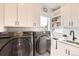 Well-equipped laundry room with modern appliances, ample storage cabinets, and a convenient sink at 8623 S Wadsworth Ct, Littleton, CO 80128