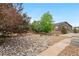 Landscaped backyard featuring stone accents, river rock detail, trees, and an exterior view of the home at 3995 Manorbrier Cir, Castle Rock, CO 80104