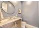 Modern powder room with stylish round mirror, elegant vanity, and textured blue walls at 2525 S Pearl St, Denver, CO 80210