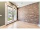 Bright living room with exposed brick wall, hardwood floors, and glass patio doors leading to the backyard at 2525 S Pearl St, Denver, CO 80210