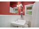 Stylish bathroom with white tiled walls, a pedestal sink, and a bright red accent wall at 726 S Corona St, Denver, CO 80209