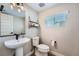 Cozy half bathroom featuring a pedestal sink, toilet, small window, and decorative shelf, creating a functional space at 16433 Askins Loop, Parker, CO 80134