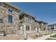 Exterior view of townhomes featuring stone and wood siding, patios with steps, and well-maintained landscaping at 16433 Askins Loop, Parker, CO 80134