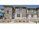 A modern townhome featuring a stone facade and a cozy front porch with light-colored railing at 16433 Askins Loop, Parker, CO 80134