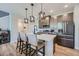 Bright kitchen with island seating, stainless appliances, stylish pendants, and wood-look flooring at 16433 Askins Loop, Parker, CO 80134