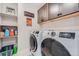 Efficient laundry room with modern washer and dryer units, overhead cabinets, and shelving for storage and organization at 16433 Askins Loop, Parker, CO 80134