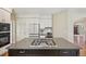 Modern kitchen with white cabinets, stainless steel appliances and large center island with cooktop at 5528 S Jasper Way, Centennial, CO 80015