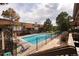 Community pool view with lounge chairs, trees, and surrounding buildings with decks at 2700 S Holly St # 202, Denver, CO 80222