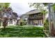 Expansive backyard featuring a multi-level deck, patio with a fireplace, lush lawn, and mature trees at 295 Jersey St, Denver, CO 80220
