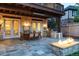 Covered stone patio with a dining set, built-in grill, and a cozy fireplace, creating an inviting outdoor space at 295 Jersey St, Denver, CO 80220