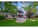 Charming backyard with a stone patio, outdoor seating, lush lawn, mature trees, and home exterior at 8927 Green Meadows Ln, Highlands Ranch, CO 80126