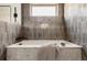 Close-up of a luxurious soaking tub with modern fixtures and elegant gray tiling at 3437 W 17Th Ave, Denver, CO 80204