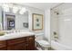 Bright white bathroom with dark vanity, framed artwork, and bathtub-shower combo at 12187 S Hidden Trail Ct, Parker, CO 80138